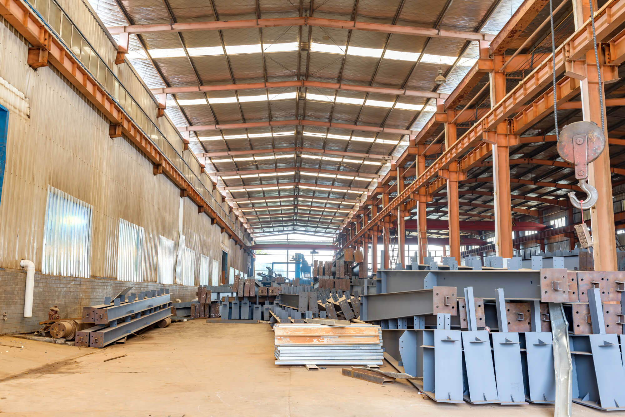 Interno di un ampio capannone con numerosi componenti metallici disposti su scaffali e pavimenti